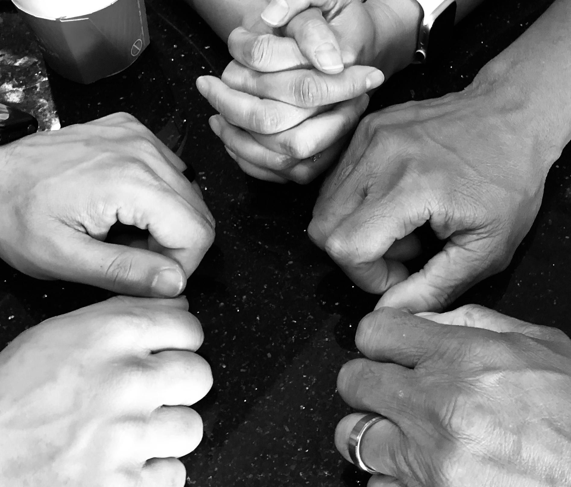 Four pairs of clasped hands in prayer